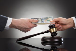 Two people passing funds over a gavel.