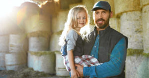 a dad holds his daughter on a farm