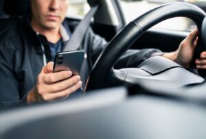 A rideshare driver looking at his phone for the location of a customer. How does liability work in Rideshare accidents?