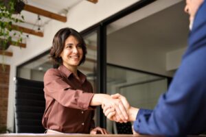 A lawyer shaking hands with her client, wondering how law firms can improve client retention.