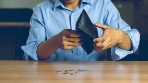 Man holds empty wallet over a table to show that he’s out of money because he can’t work while his lawsuit is pending.